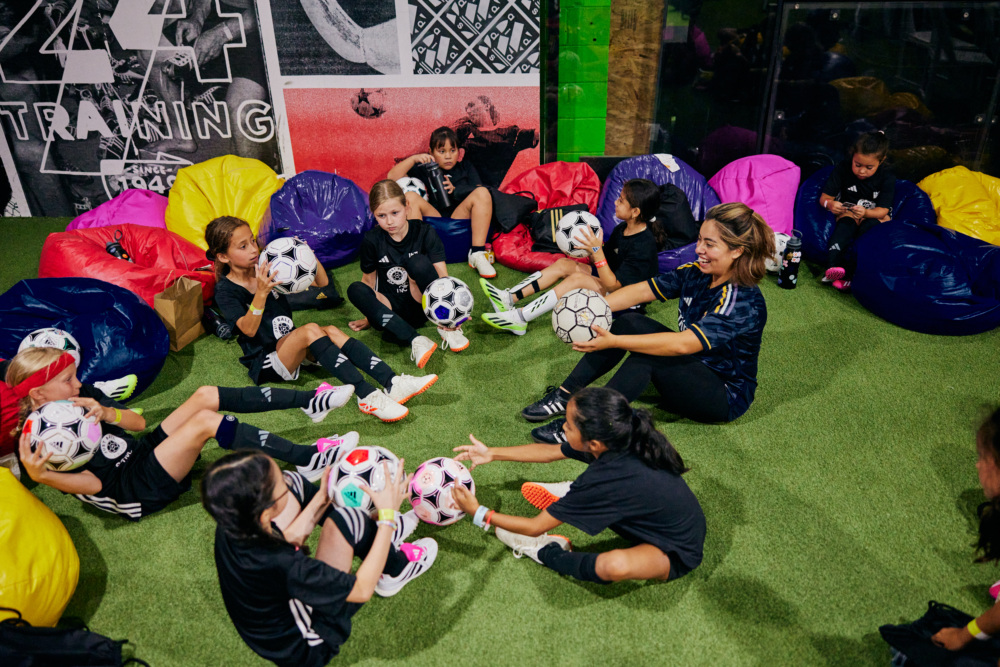 A group of girls learn soccer tricks with a soccer freestyler